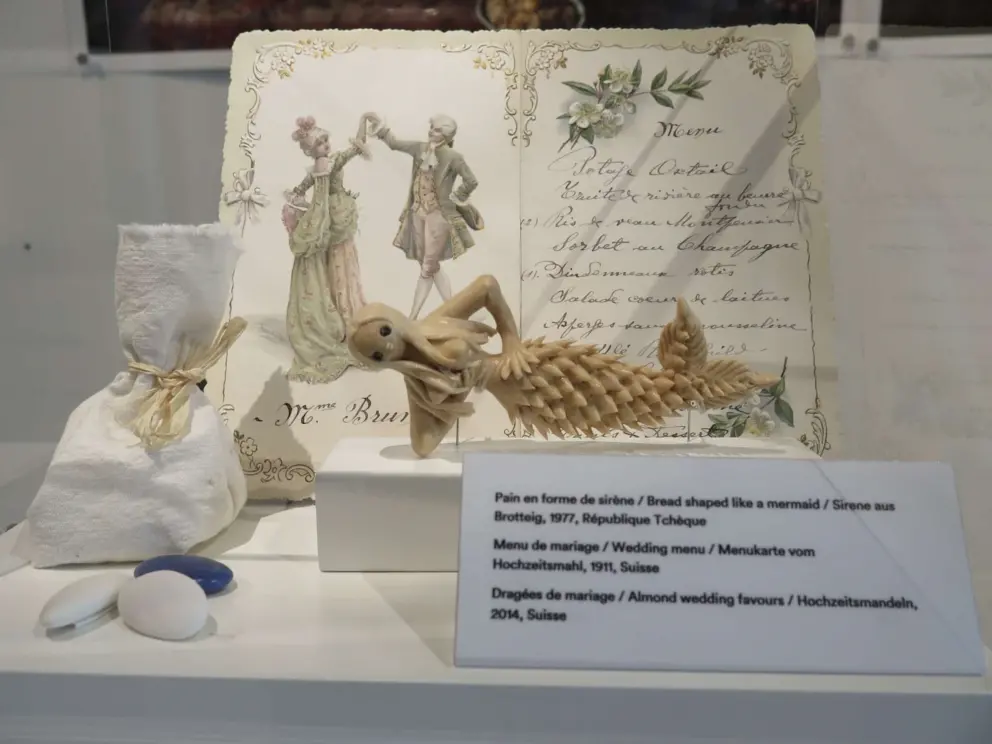 Bread shaped like a mermaid, wedding menu, and almond wedding favors. 