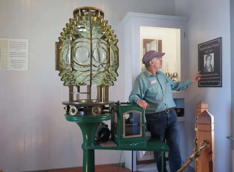 A docent explains the fresnel lens. 