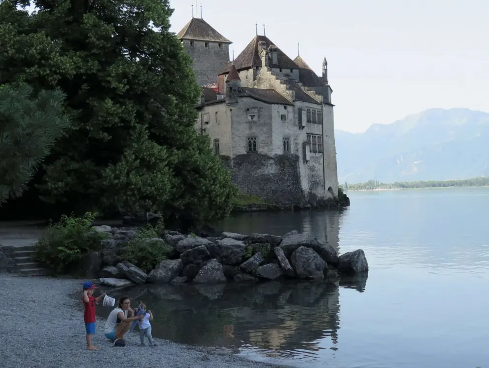 A mom and two kids play on the beach by the castle. 