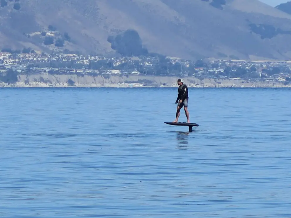 Foil surfer with cliffs behind. 