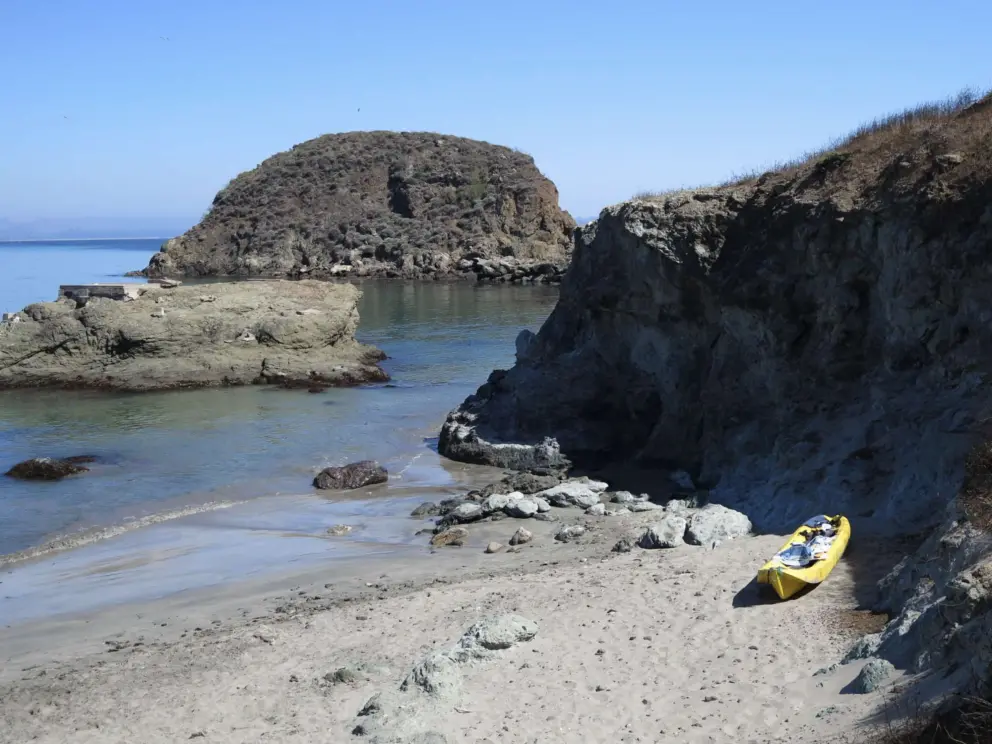 A  yellow kayak by the cliffs. 