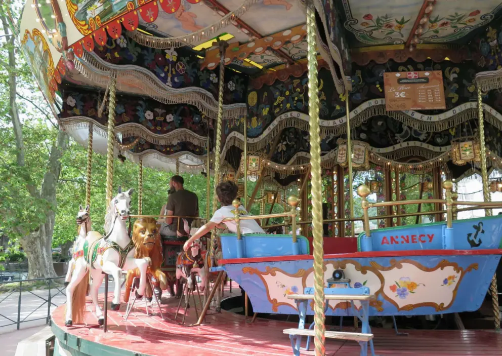 A boy riding in the boat on the carousel. 