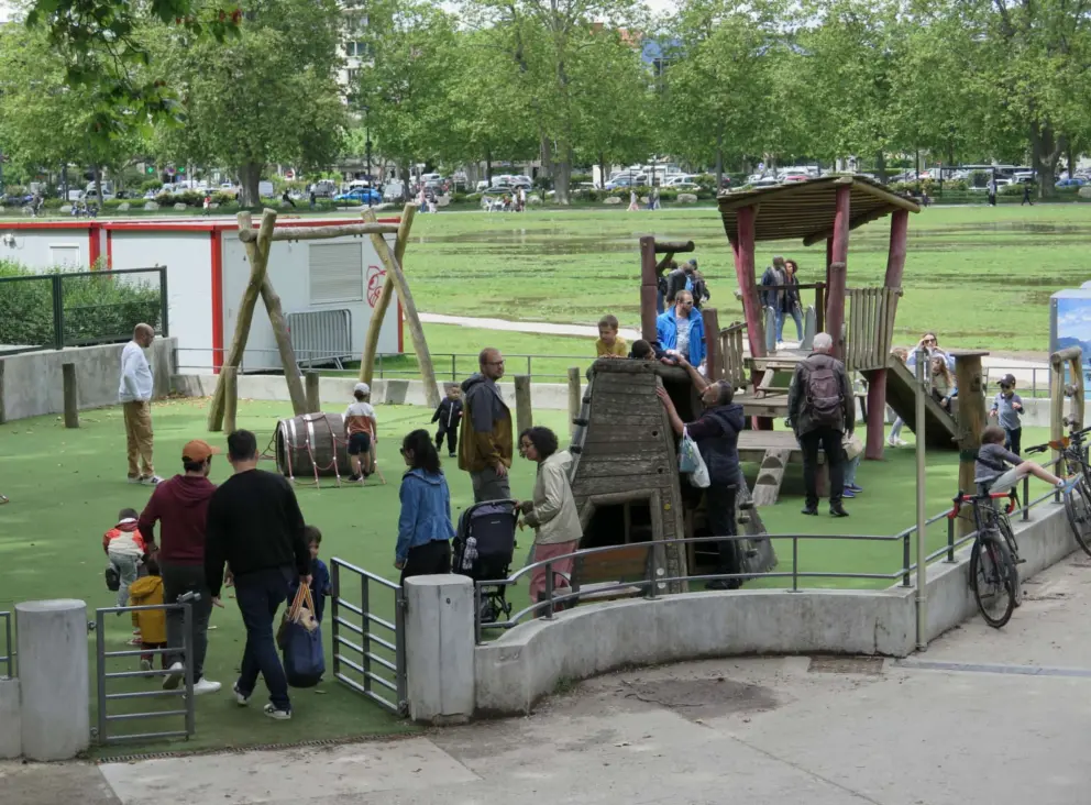 Barrel, rock climbing, and wooden structure with slide at Parc des Enfants.  