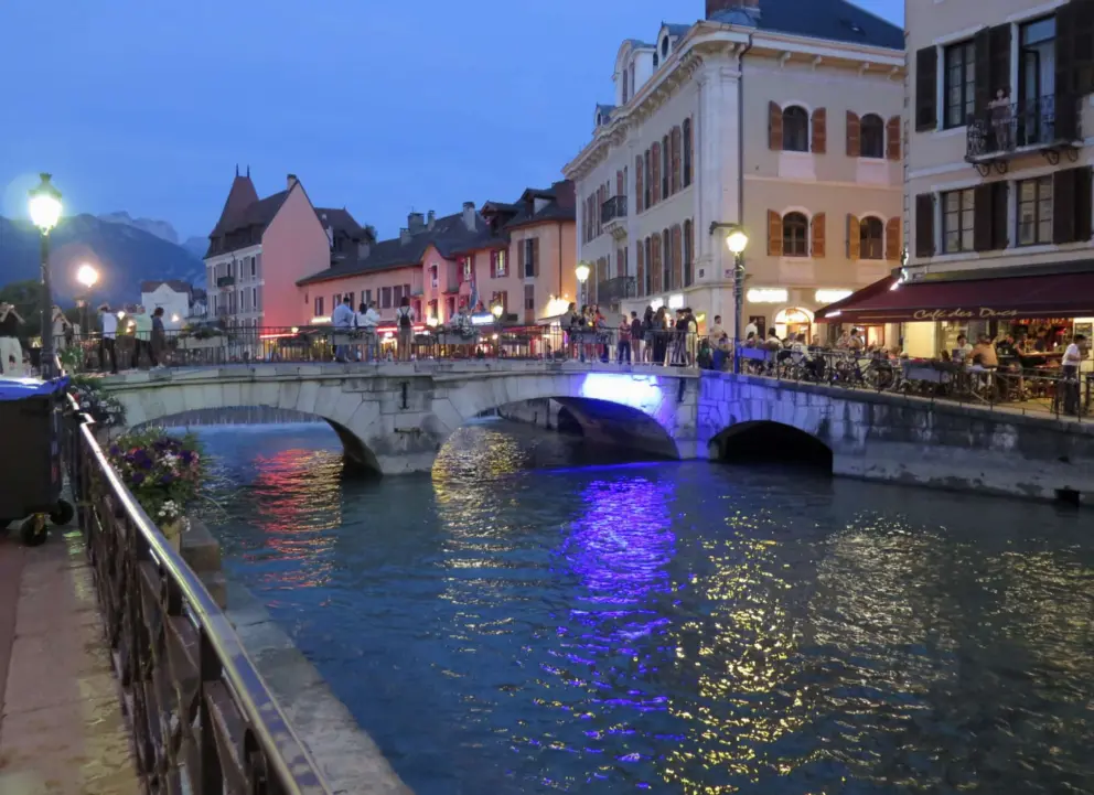Pont Perriere over the blue-green river, lit at night. 