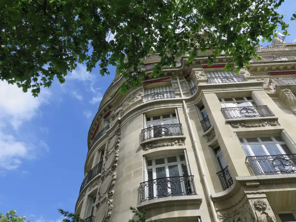 Ironwork balconies and leafy branches, along the Champ de Mars. 