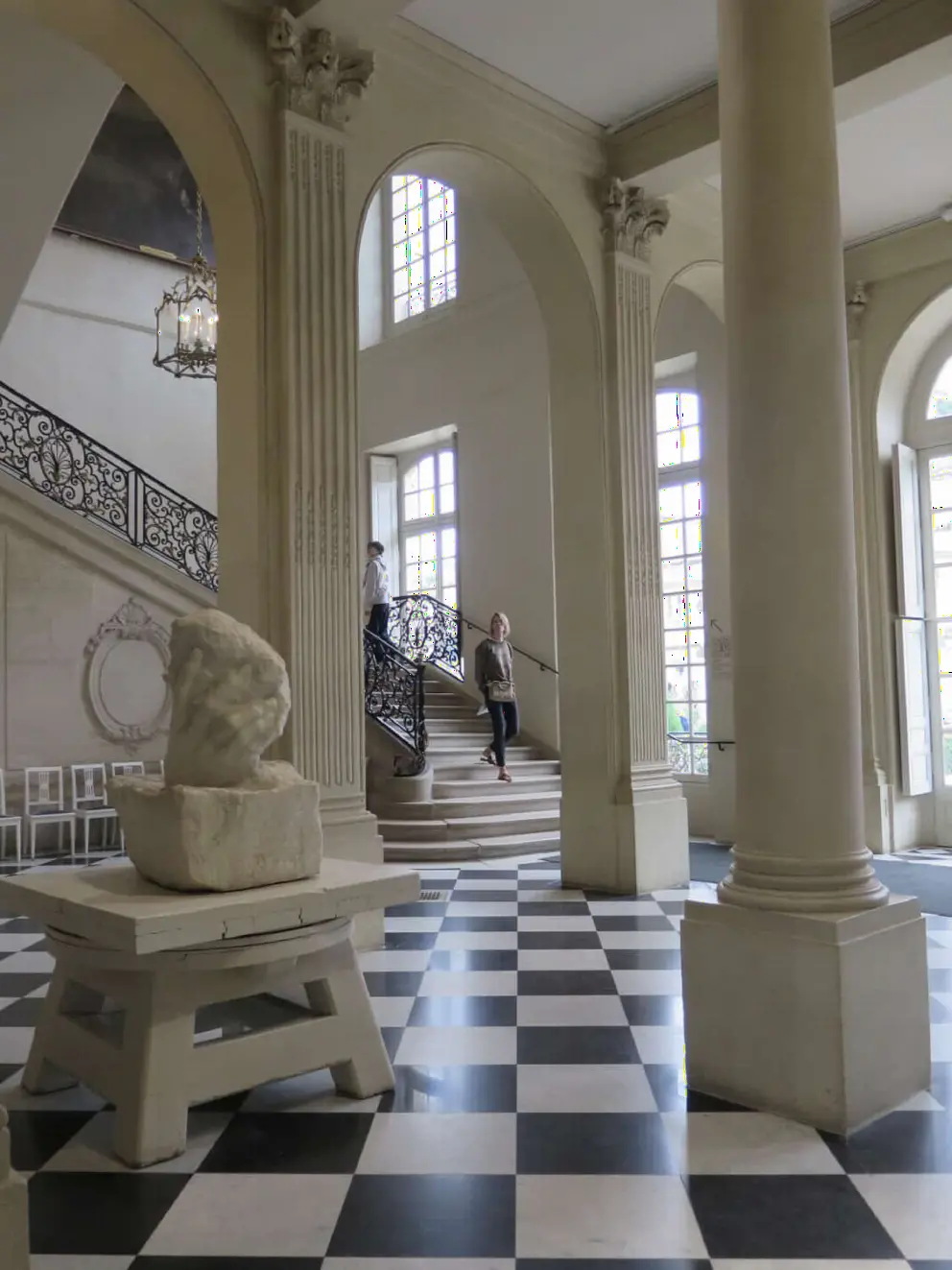 The downstairs room with checkered floor, arched windows, and columns.