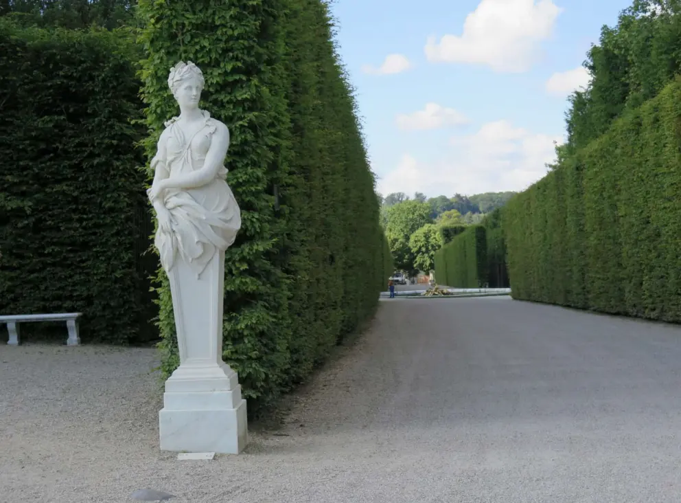 Rows of tall hedges and a sculpture. 