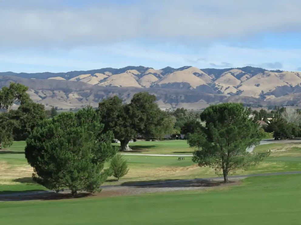 Golf course with mountain range in the sun. 