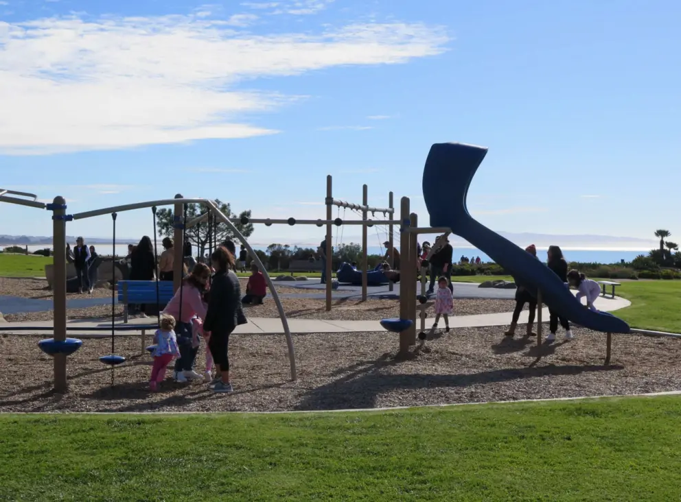 Parents and kids at the playground, with views of the sea. 