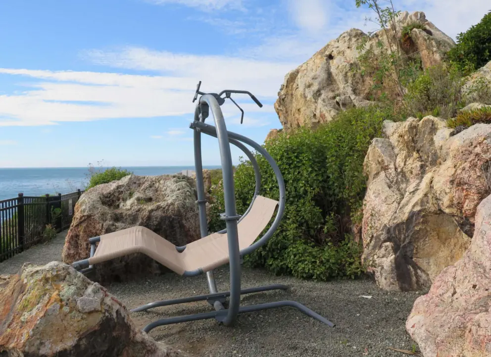 You walk past a swinging chair and boulders on the trail that goes in front of Inn at the Cove. 