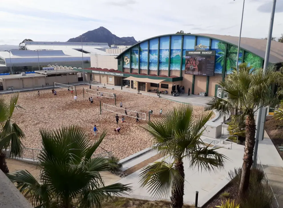 The sand volleyball court has a tropical backdrop. 