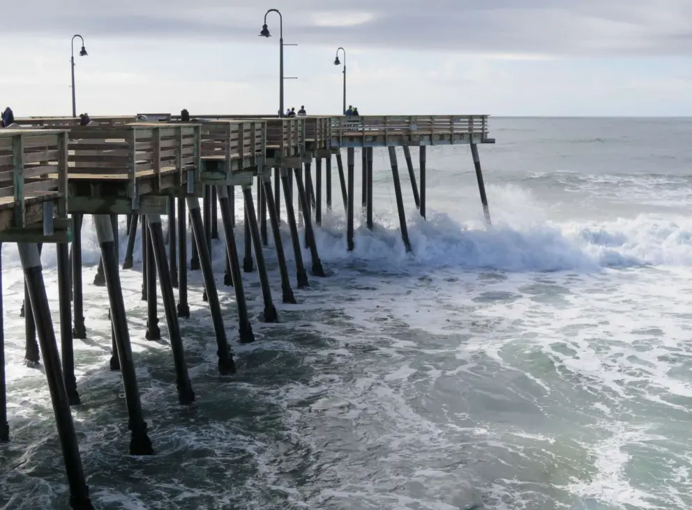 Waves crash against the pier pilons. 