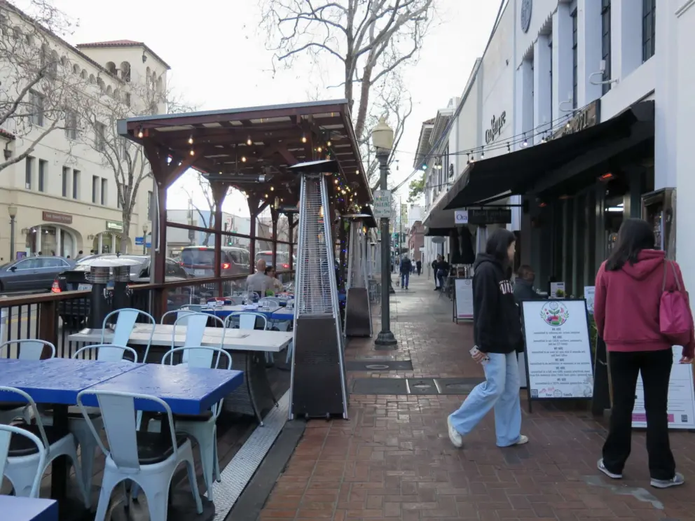 Outdoor seating and heat lamps at a cafe. 