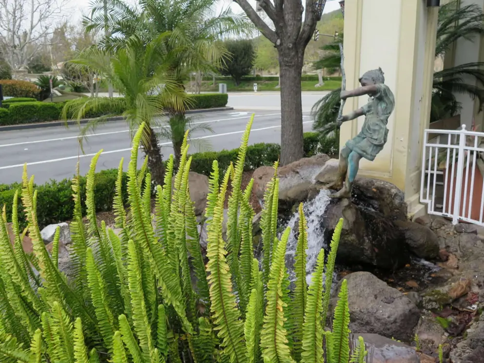 Statue of children playing by a fountain, at a cafe. 
