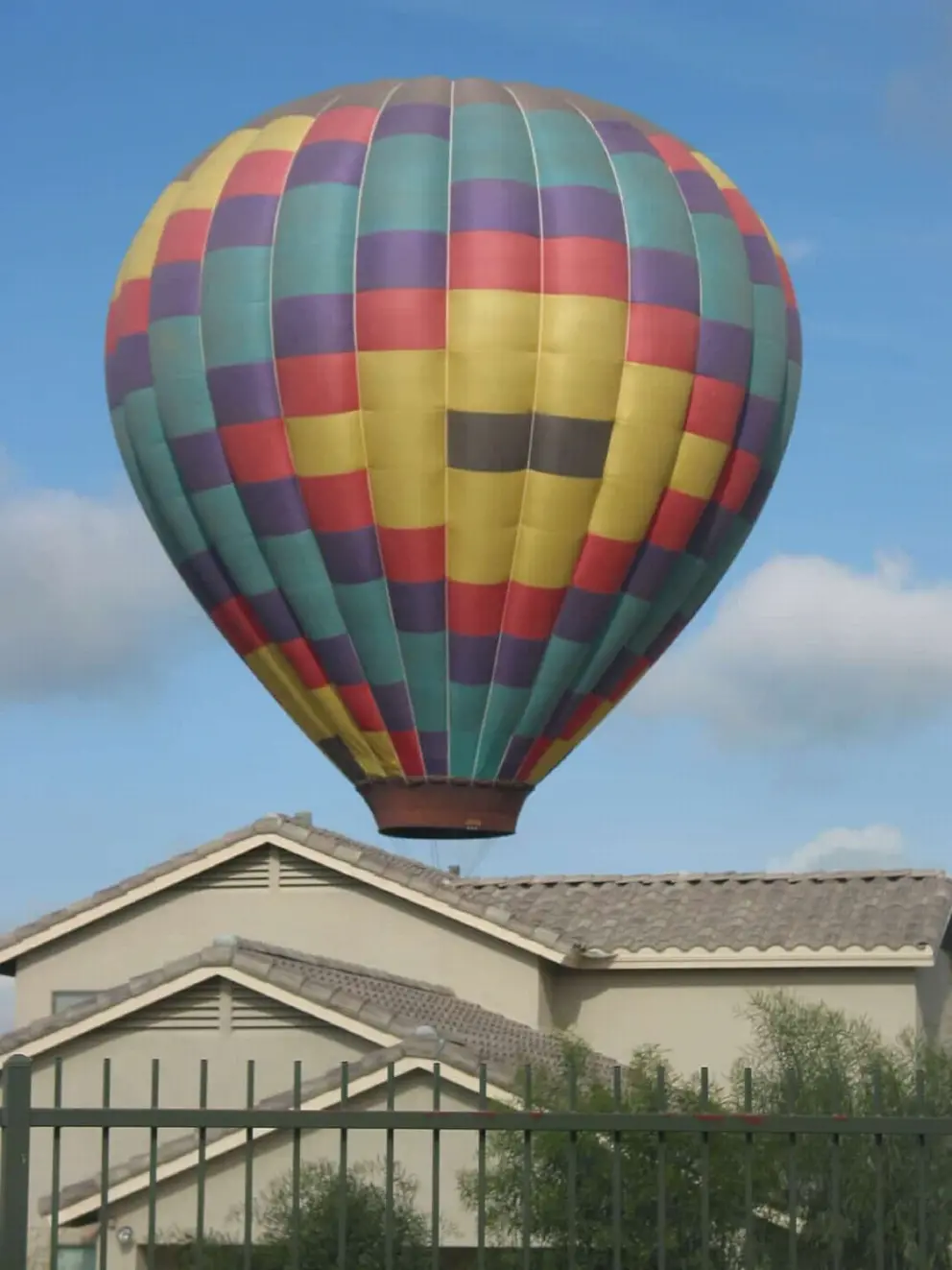A hot air balloon lands behind a house. 