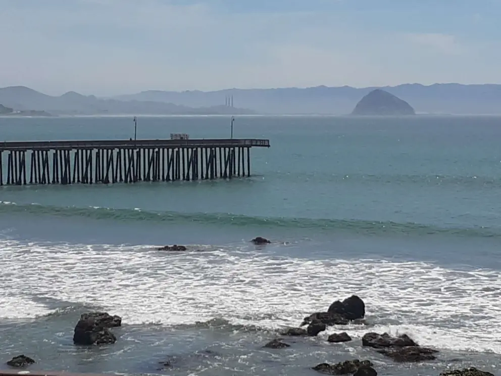 View of Morro Rock and Cayucos Pier, with waves rolling in. 
