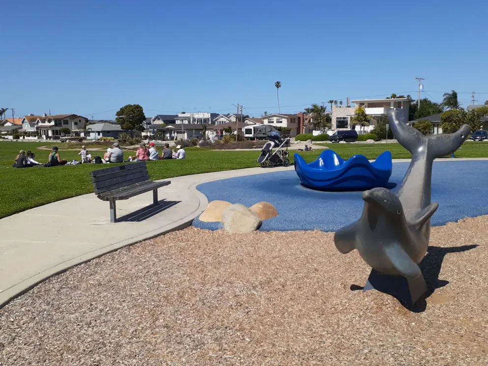 Dolphin statues, four-person spinner, and group of moms gathered on the lawn. 