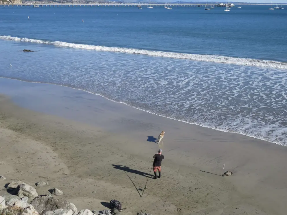 A man fishing with his dog. 