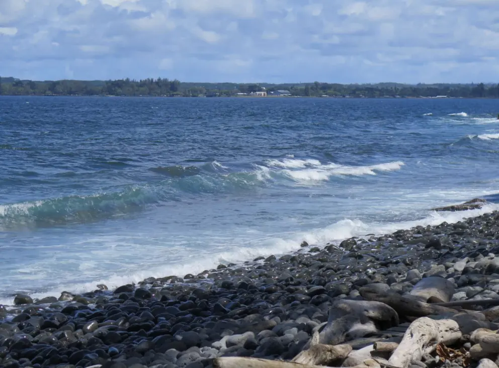 Rocks on the shore, and creamy blue water. 