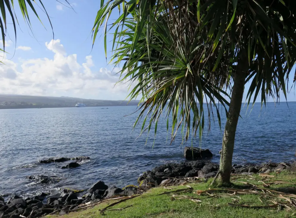 Views of Mauna Kea and the sea splashing on rocks, near Hilo Bay Cafe. 