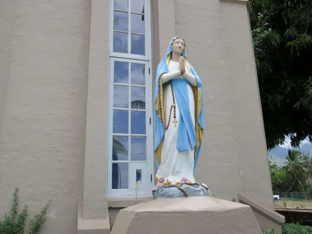 Statue of Mary praying with a rosary.