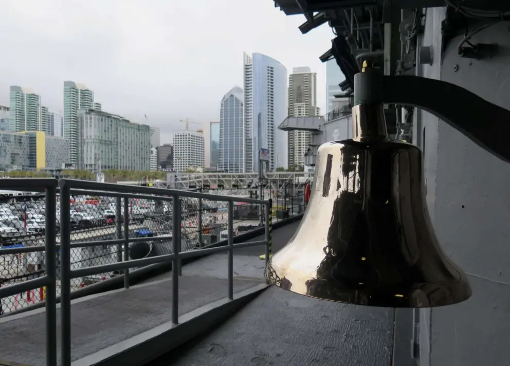 A bell, with the city skyline in the distance. 