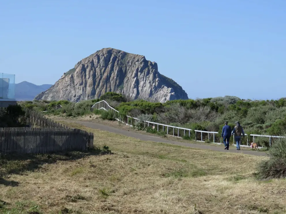A couple walks along the path with views of Morro Rock. 