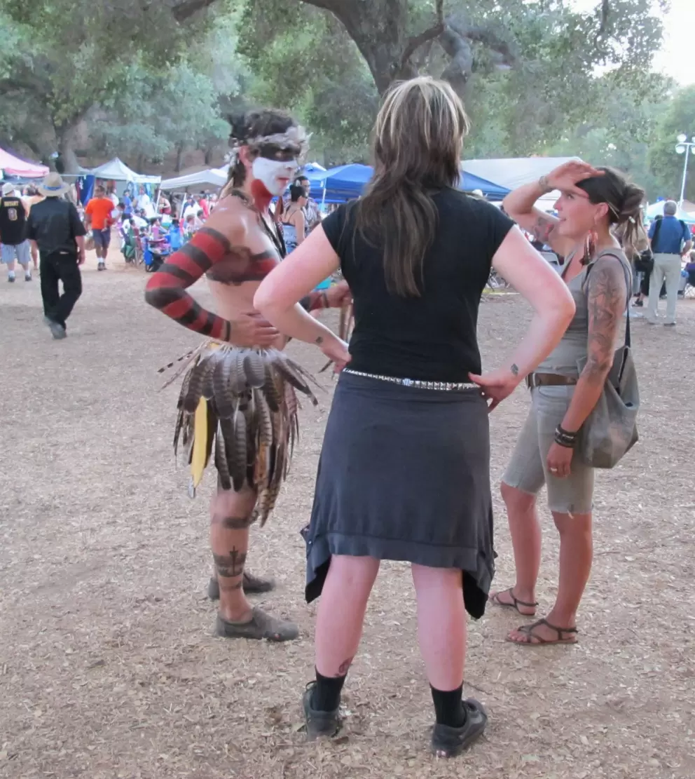 A man with feather head-piece and painted arms.