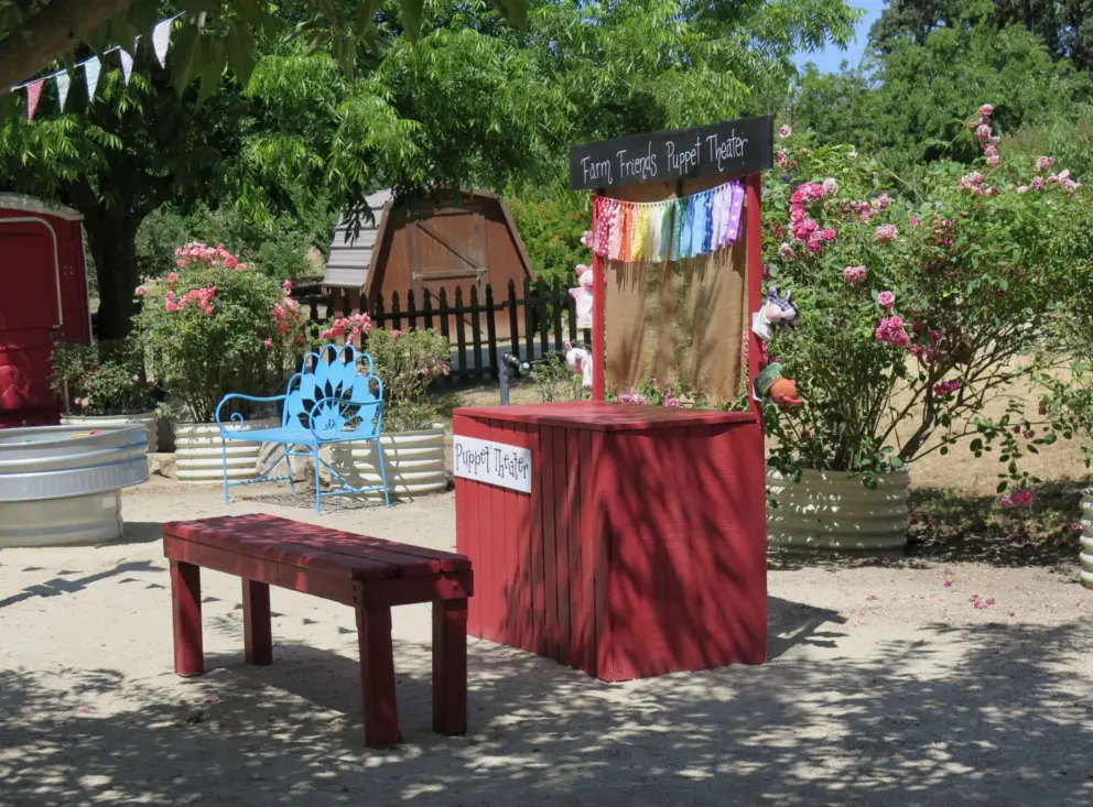 Puppet theater, with roses behind. 