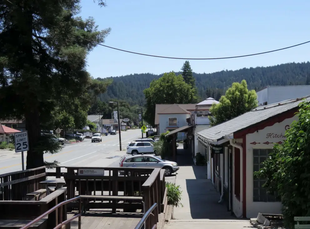 Redwood tree and deck, along Highway 9, with forested hills in the distance. 