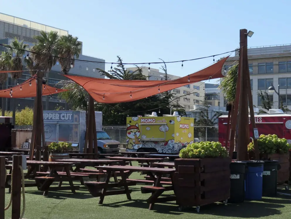 Picnic tables outside food trucks at Spark Social SF. 