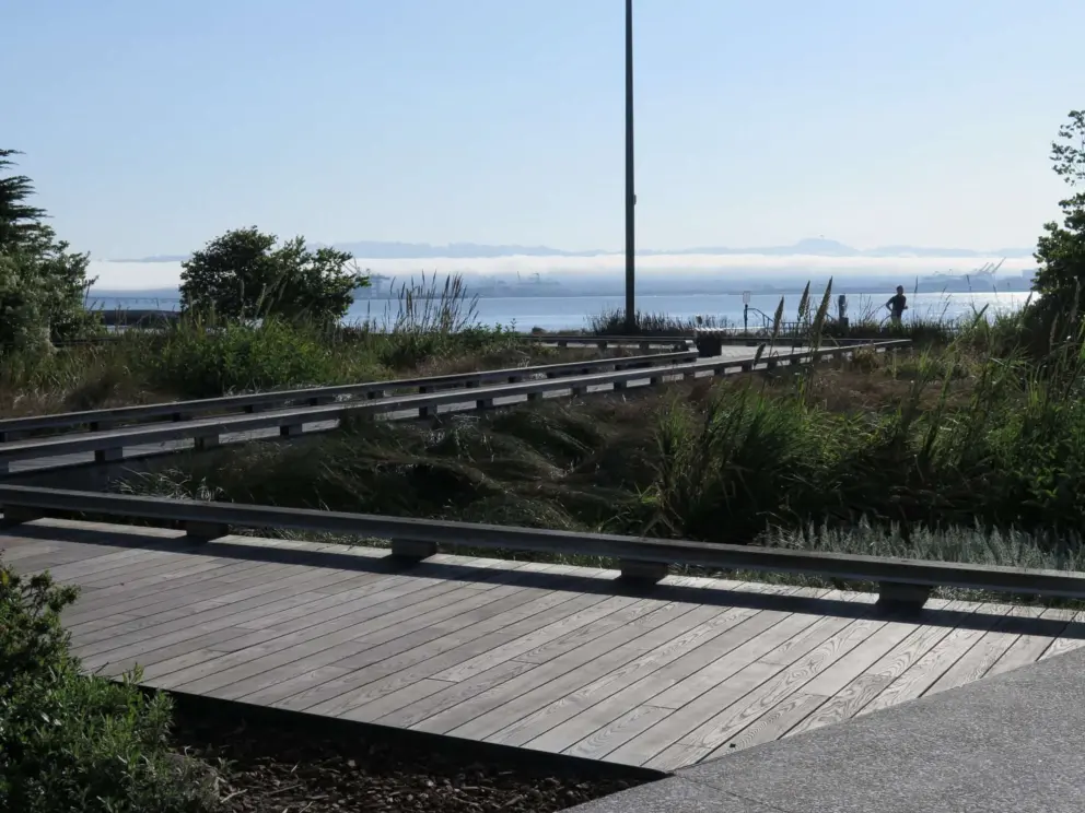 Wooden boardwalk, runner, and water views, at China Basin Park. 