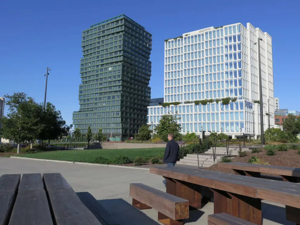 Log picnic tables and modern buildings at China Basin Park. 