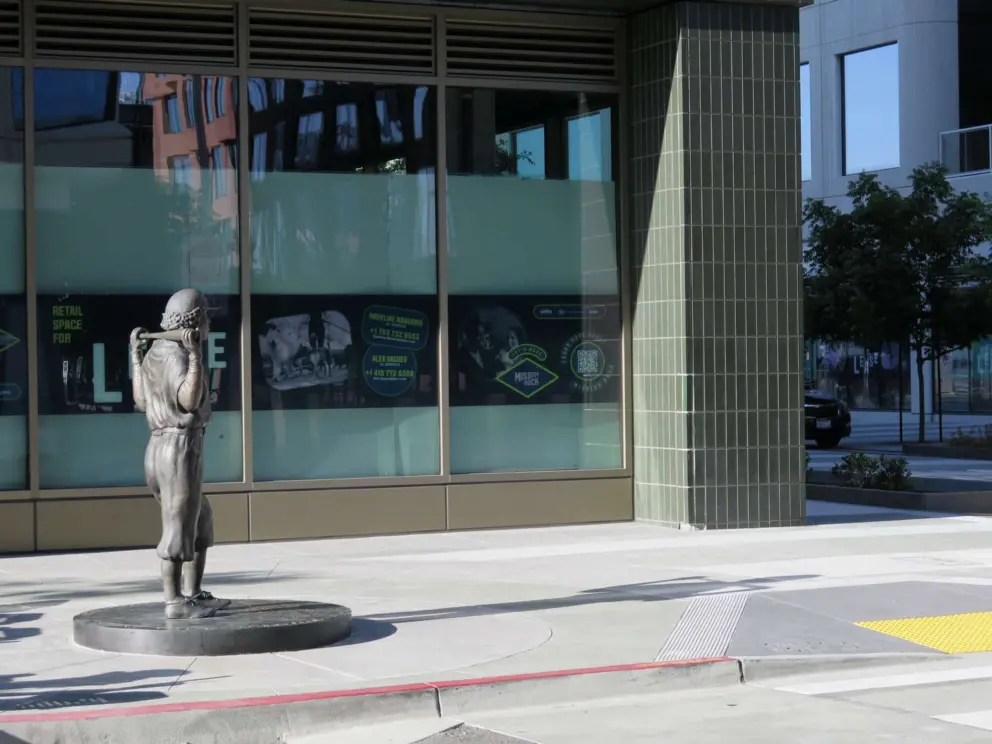 Baseball player statue near a commercial space. 
