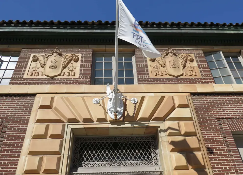 Port of San Francisco Post Office building, made of brick with terracotta trim, a phoenix and flagpole above the door, and two terracotta shields in brick panels. 