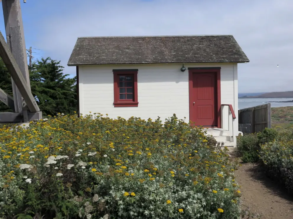 A cute sight, this little cottage with red trim, and flowers in front. 