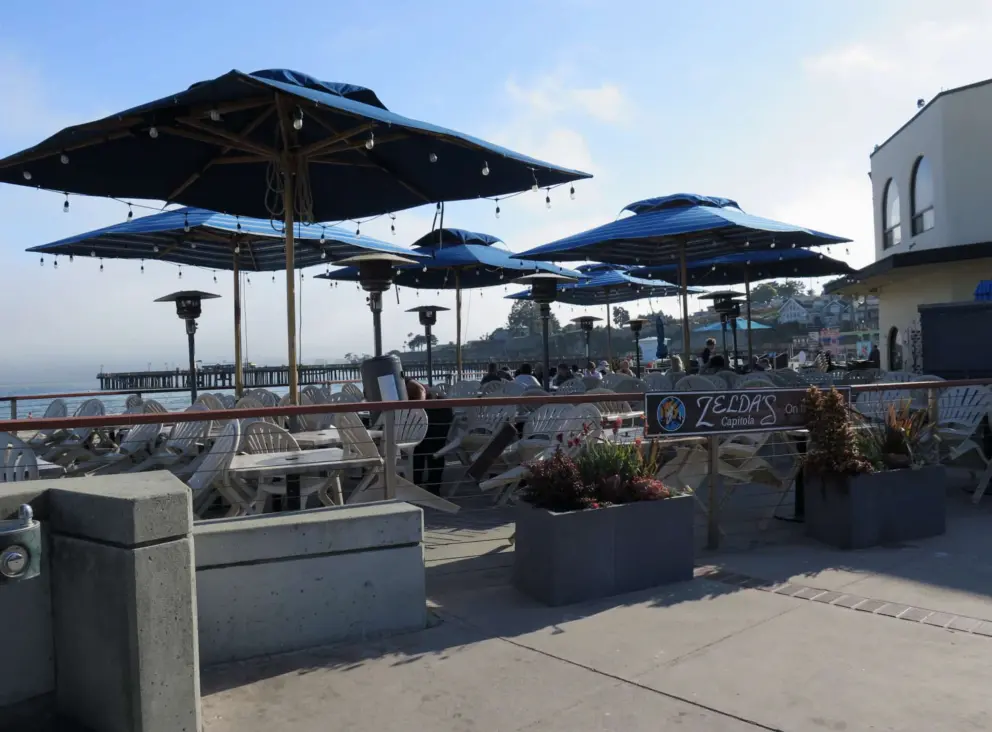 Zelda's on the Beach, with blue umbrellas and views of the pier. 