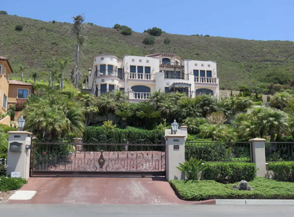 A mansion with a curlicue ironwork fence. 