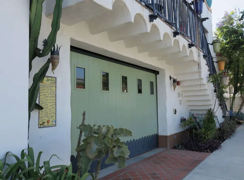 Green garage door, cactus, curved lines, and colorful flower pots at El Jardin.