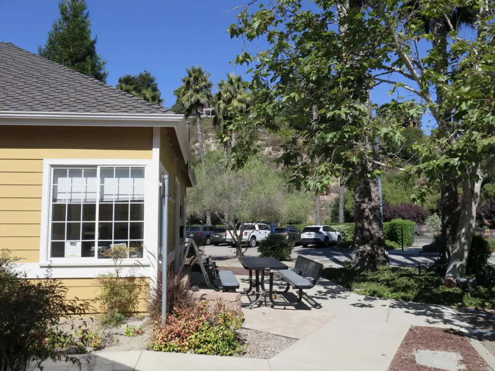 Yellow office and picnic table under trees at Avila Village. 