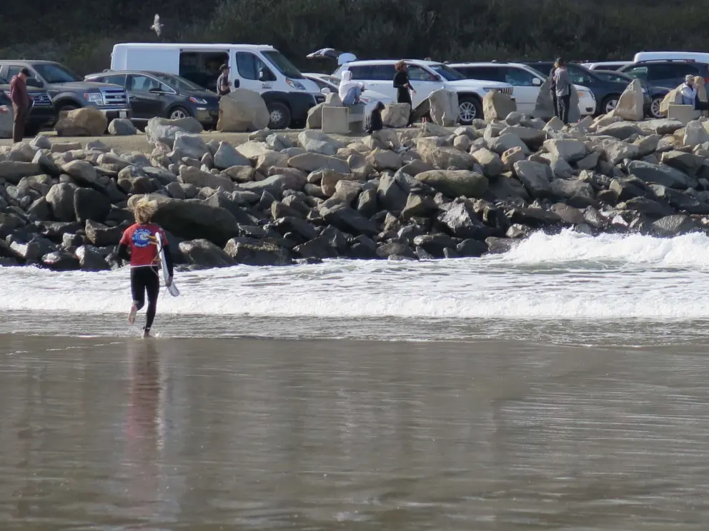 A surfer runs into the water. 