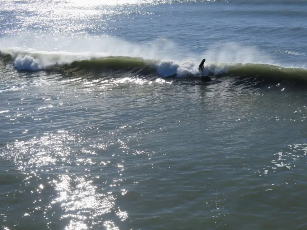 Surfer, sea spray, and light behind the wave. 