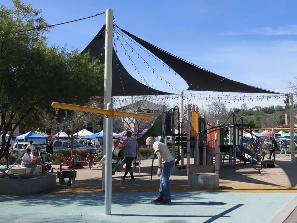 Parents playing with their kids at in Downtown City Park Playground on a Saturday morning. 