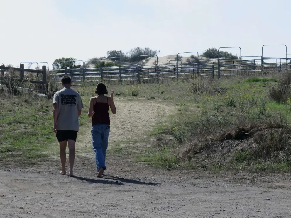 A young couple walk from the grey building toward the RV campground. 