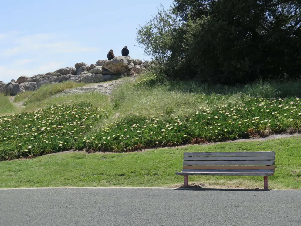 Two people sit on rocks at the lookout where you can see Pismo Beach below!