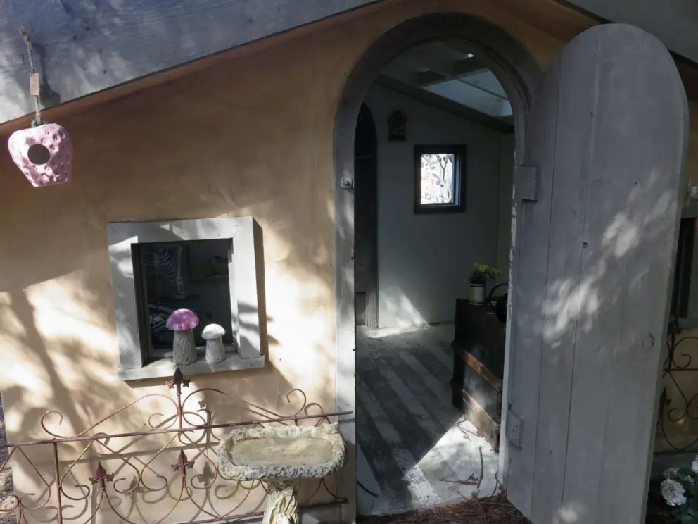 The door to the cottage, and window with mushroom sculptures. 
