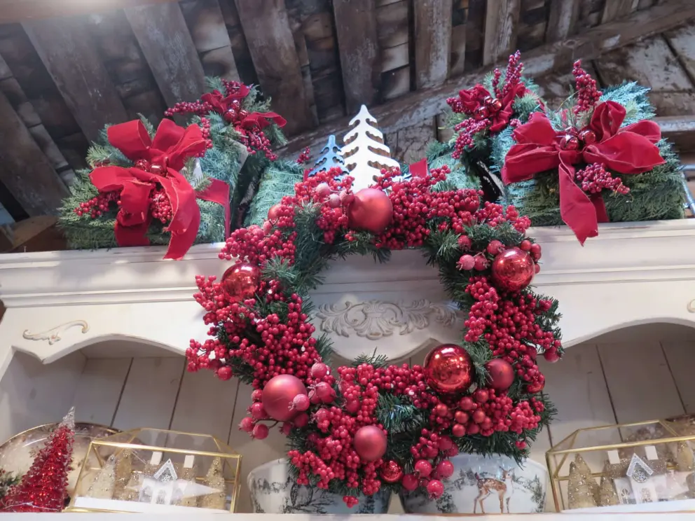 Red wreath with berries, bows, and wooden ceiling. 