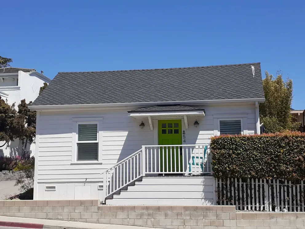 A cute little house with green door, on a side street. 