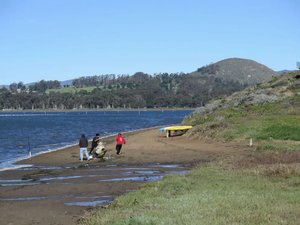 People fishing at Pasadena Drive Coastal Access, with volcanic mountain in the distance. 