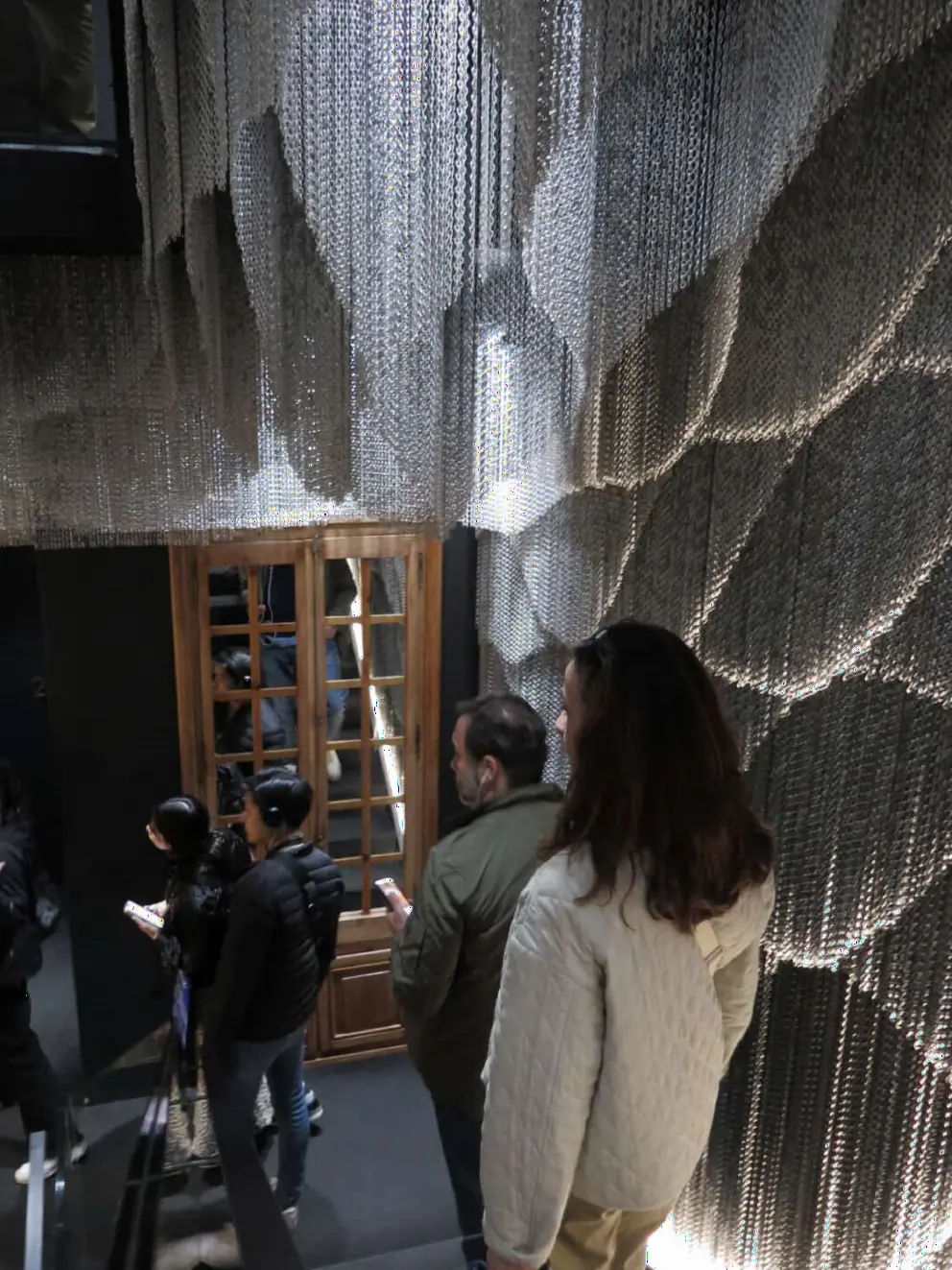 The undulating shapes of hung aluminum chains, in the evacuation staircase. 